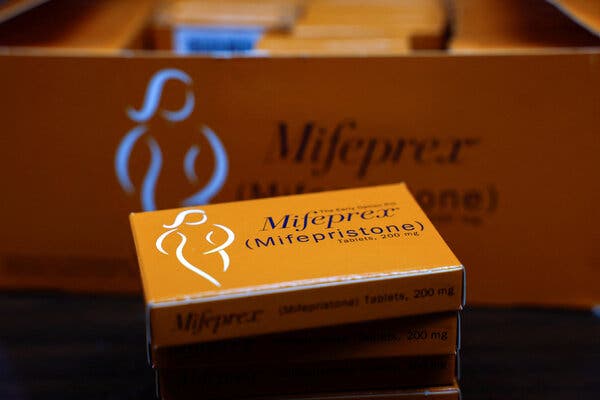 A close-up view of a small orange box of mifepristone in front of a larger box, also orange.