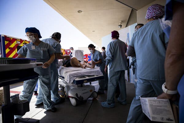 People in scrubs and face masks surround a person on a stretcher.