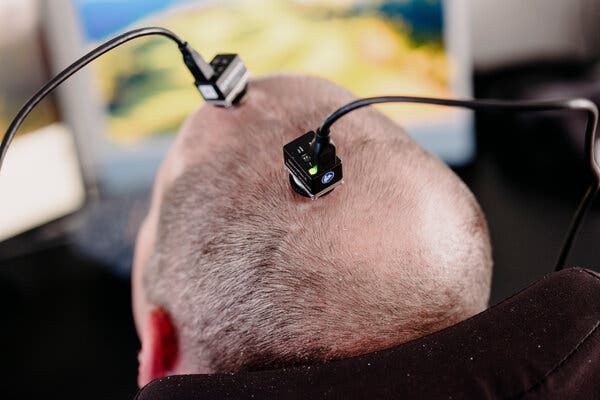 A close-up view of two devices that connect from the skull of a man to a computer out of frame.