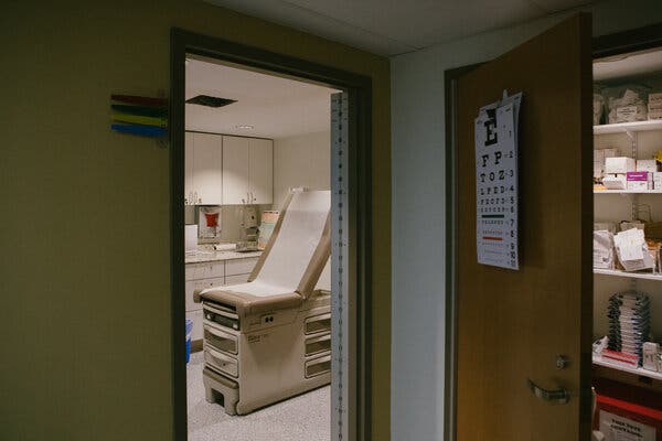 A view from a hallway into an exam room of a health care center.