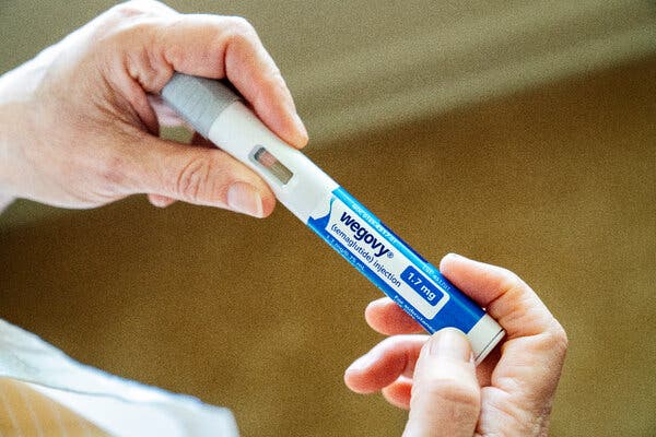 A person holds a Wegovy injection pen in their hands.