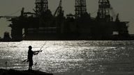 FILE - A man wears a face mark as he fishes near docked oil drilling platforms on May 8, 2020, in Port Aransas, Texas. The U.S. government has accepted nearly $190 million in bids from an offshore oil and gas lease sale that was held nearly a year ago but rejected by a federal judge, the Bureau of Ocean Energy Management said Wednesday, Sept. 14, 2022. (AP Photo/Eric Gay, File)