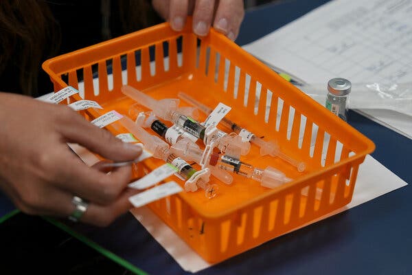 23aluminum-01-articlelarge An orange tray of childhood vaccines with a person's hands applying labels to its edge.