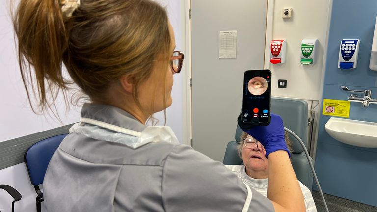 Nina Glazzard, an advanced clinical practitioner for ears, nose and throat, using an endoscope-I adapter on Janet Hennessy, 76, from Bradeley, Stoke-on-Trent, as part of a trial at North Midlands University Hospitals NHS Trust. The adapter includes a 32mm lens that attaches to an iPhone, turning it into a portable endoscope to help the NHS rule out throat cancer in patients faster. Issue date: Saturday November 2, 2024.