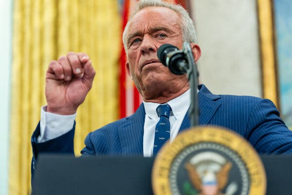 00measles-kennedy-01-tkpq-articlelarge Robert F. Kennedy Jr. speaks from a lectern in the Oval Office and gestures with his right hand.
