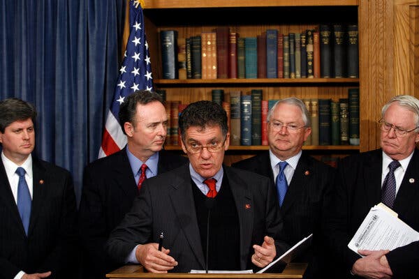 13hs-weldon-cdc-zcpw-articlelarge Dr. Dave Weldon, in a dark suit with a black vest and red tie, speaks from a lectern, flanked by other men in suits during a news conference in 2007.
